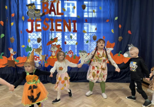 Dzieci z grupy IV trzymają się za ręce, stojąc w półkolu.