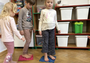 Dzieci chodzą gołymi stopami po ścieżce sensorycznej.