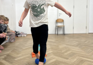 Dziecko chodzi gołymi stopami po ścieżce sensorycznej.