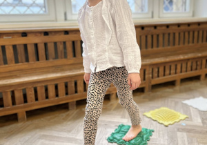 Dziecko chodzi gołymi stopami po ścieżce sensorycznej.