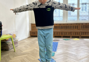 Dziecko chodzi gołymi stopami po ścieżce sensorycznej.