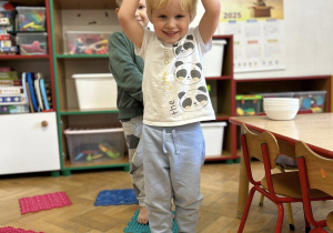 Dzieci chodzą gołymi stopami po ścieżce sensorycznej.