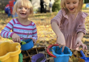 Dwie dziewczynki bawią się w błocie.