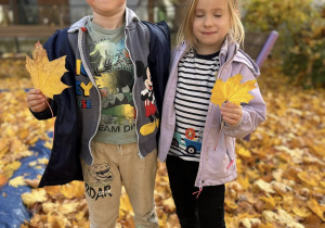 Chłopiec i dziewczynka trzymają w rączkach liście.