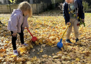 Chłopiec z dziewczynką grabią liście.