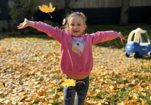 Dziecko podrzuca liście do góry.