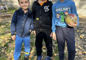 Trzech chłopców z grupy IV stoją obok siebie i pozują do zdjęcia.