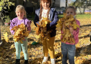 Dzieci trzymają w rączkach liście.