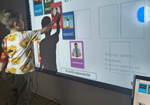 Dziecko wykonuje zadanie na tablicy multimedialnej.