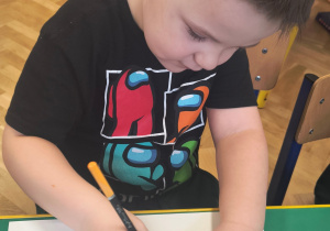 Chłopiec rysuje buzie z wybraną emocją.