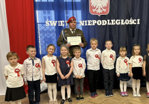 Dzieci stoją w rzędzie na tle dekoracji.