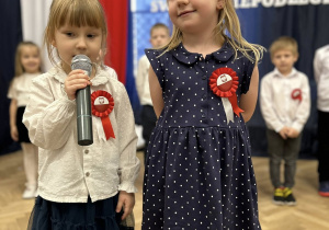 Stoją dwie dziewczynki na środku sali. Jedna z dziewczynek mówi wiersz.