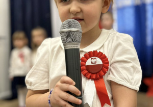Dziewczynka mówi wiersz do mikrofonu.