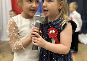 Dwie dziewczynki mówią wiersz do mikrofonu.