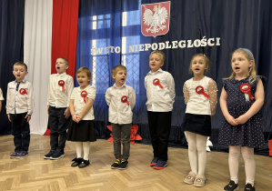 Dzieci stoją w rzędzie na tle dekoracji.