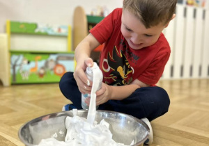 Dziecko wrzuca do miski piankę do golenia.