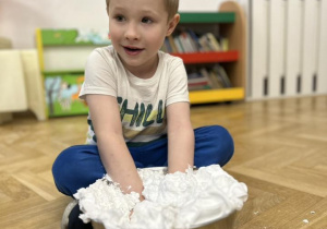 Dziecko włożyło ręce do miski z pianką do golenia.