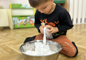 Dziecko wrzuca do miski piankę do golenia.