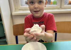 Dziecko pokazuje kulkę z piankoliny.