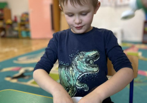 Dziecko w miseczce ugniata piankolinę.