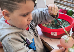 Dziecko ozdabia bombkę.