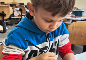 Dziecko ozdabia bombkę.