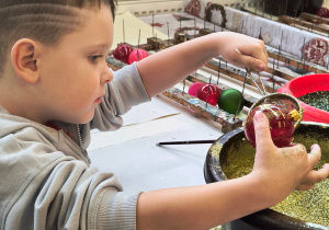 Dziecko ozdabia bombkę.