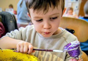 Dziecko ozdabia bombkę.