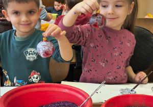 Dzieci pokazują ozdobione przez siebie bombki.