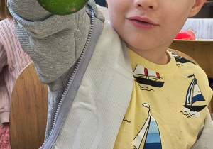 Dziecko pokazuję ozdobioną przez siebie bombkę.