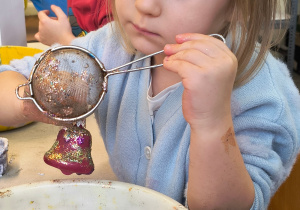 Dziecko ozdabia bombkę.