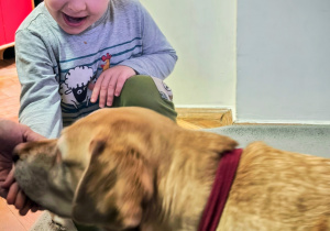 Dziecko głaszcze psa.