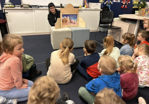 Dzieci z grupy 4 siedzą przed teatrzykiem i słuchają bajki.