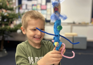 Chłopiec pokazuje swoją kukiełkę wykonana z łyżki i innych materiałów.