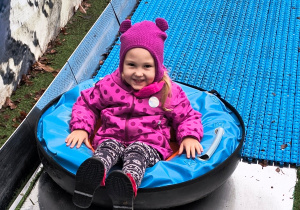 Dziecko zjeżdża na pontonie ze zjeżdżalni.