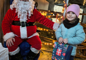 Dziecko odbiera od Mikołaja prezent.