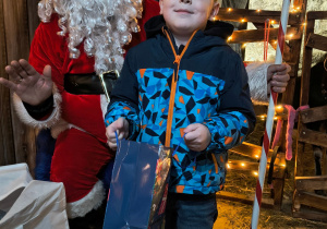 Dziecko odbiera od Mikołaja prezent.