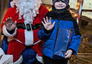 Dziecko odbiera od Mikołaja prezent.