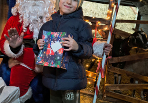 Dziecko odbiera od Mikołaja prezent.