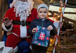 Dziecko odbiera od Mikołaja prezent.