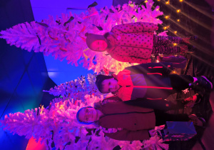 Dzieci stoją na tle dekoracji świątecznej.