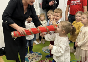 Pani Dyrektor przykłada kredkę do ramienia dziewczynki.