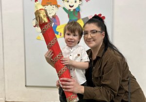 Chłopiec z mamą trzyma kredkę podczas pasowania.