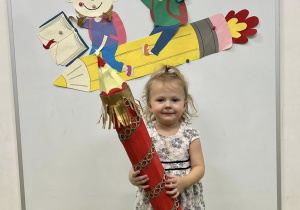 Dziewczynka trzyma kredkę podczas pasowania.