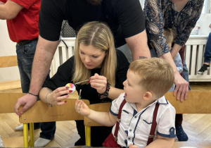 Dzieci z rodzicami ozdabiają styropianowe ozdoby.