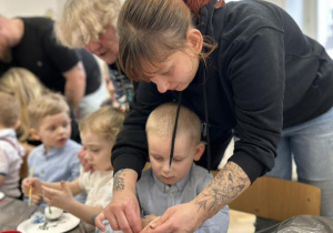 Dzieci z rodzicami ozdabiają styropianowe ozdoby.