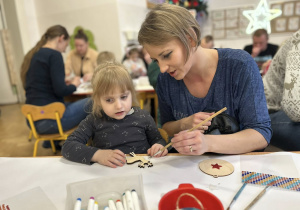 Dziewczynka z mamą przygotowuje świąteczną ozdobę - bombkę.