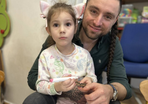 Dziewczynka z tatą przygotowuje świąteczną ozdobę - bombkę.