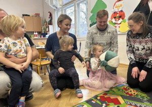 Dzieci z grupy II siedzą w dużym kole z rodzicami.