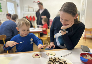 Chłopiec z mamą przygotowuje świąteczną ozdobę - bombkę.